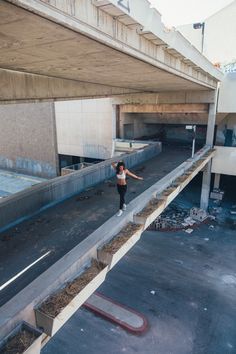 a woman is standing in the middle of an empty parking lot with her arms outstretched