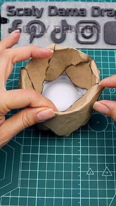 two hands holding a piece of paper over a hole in the middle of a sheet of cardboard