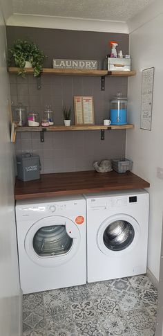 a washer and dryer in a small room with shelves on the wall above them