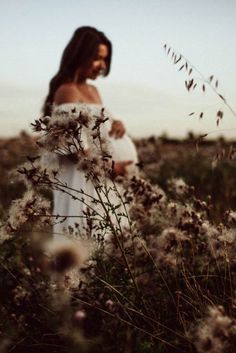 a pregnant woman standing in a field of flowers