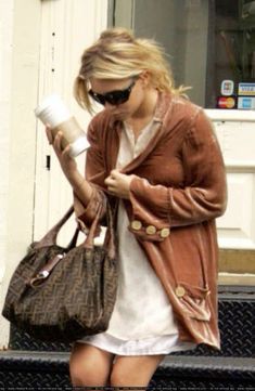 a woman is walking down the street while holding a coffee cup