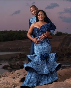 a man and woman are standing on some rocks