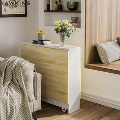 a living room with a couch, book shelf and flowers in a vase on the table