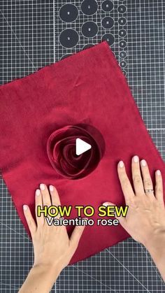 someone is making a flower out of red fabric with their hands on the edge of it