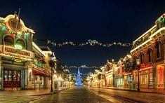 an empty street at night with christmas lights on the buildings and trees in the background