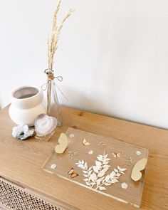 a vase with some flowers on top of a wooden table next to a glass plate