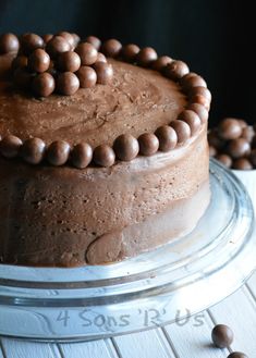 a chocolate cake sitting on top of a glass platter next to some candy balls