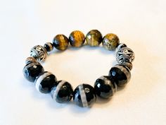 Large Tiger Eye and Black Agate Beaded Bracelet.  Sold as individual units.  7.5 inches  Size can be adjusted. Please allow two additional days for size adjustments.  Some images show multiple images for styling tips#blackfridaysale #blackfridaydeals #trecieshoppe #giftsforhim #giftsforher #giftideas #christmasgifts #armcandy #bracletstacks #bracelets #jewelry#bhm #womanownedbusiness #blackownedbusiness #treciesshoppe #trecies #armcandy #braceletstacks #mensstyle #sytleinspiration #Womensstyle # Black Adjustable Stretch Bracelet With Gemstone Beads, Adjustable Onyx Stretch Bracelet With Gemstone Beads, Adjustable Onyx Stretch Bracelet With Round Beads, Casual Black Stretch Bracelet With Gemstone Beads, Black Bohemian Bracelets With Faceted Beads, Bohemian Black Beaded Bracelets With Faceted Beads, Black Bohemian Beaded Bracelets With Faceted Beads, Bohemian Black Beaded Bracelet With Faceted Beads, Casual Black Gemstone Beads