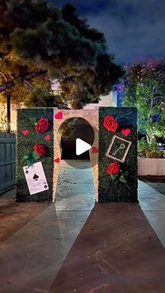 an entrance to a garden at night with roses and cards on the door, surrounded by greenery