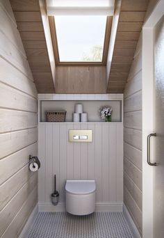 a small bathroom with a skylight above the toilet and shelves on the wall behind it