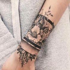 a woman's arm with flowers on it and a black ribbon around the wrist