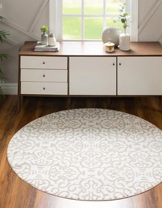 a white rug sitting on top of a wooden floor next to a dresser and window