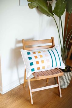 a wooden chair sitting next to a potted plant on top of a hard wood floor