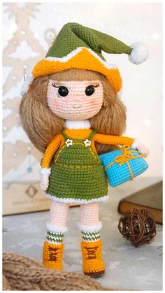 a crocheted doll with a green dress and yellow hat holding a blue bag