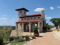 a large house with a tall tower on top of it's roof next to a dirt road