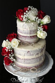 a three tiered wedding cake with red and white flowers