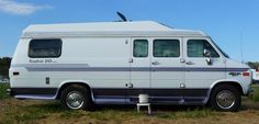 an old white van parked in the grass