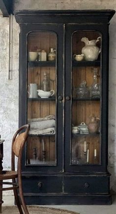 an old china cabinet with glass doors and dishes on it's shelves in the corner