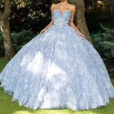 a woman in a blue ball gown standing next to a tree