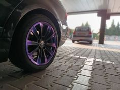 a car is parked in front of a gas station with purple wheels and rims