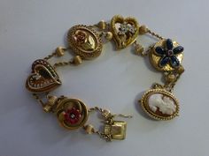 "This unique bracelet has 5 large slides and a cameo clasp. First slide is a red enamel flower with a small diamond center, second slide is heart shaped with a diamond ,emerald and ruby stone heart on top,( the back is engraved \"Christmas 2002\"), third is a 3D rose gold flower, fourth is heart shaped and has 3 blue enamel flowers, and the fifth one has 5 sapphire cabochon oval stones representing a flower with a little ruby center. There is a total of 12 , 5mm corrugated gold beads used to sep Dope Jewelry Accessories, Sapphire Cabochon, Slide Bracelet, Rose Gold Flower, 3d Rose, Dope Jewelry, Funky Jewelry, Jewelry Lookbook, Ruby Stone