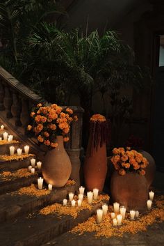 several vases with flowers and candles on the steps