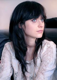 a woman with long black hair sitting on a couch