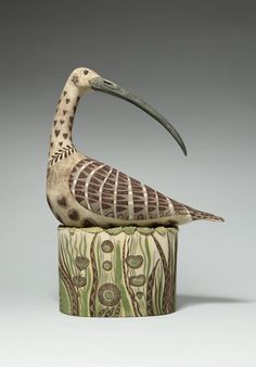 a bird statue sitting on top of a wooden stump with an intricate design around it's neck