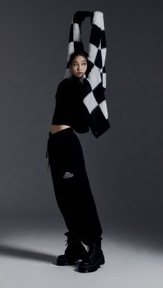 a woman in black and white poses with a checkerboard scarf on her head