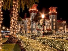 a large building with christmas lights on it's sides and palm trees in the foreground