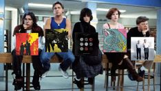 several people sitting at a table with posters on them and one person holding a book