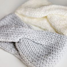 two knitted blankets laying on top of each other in white and grey color scheme