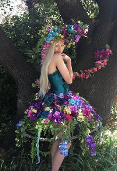 Recycled Renaissance, where Plain meets Haute Couture and the simplest dress is made Runway Ready!😊  This pictured Tropical Extravaganza began with a plain white one-size-fits-most hoop skirt which I started cutting apart to make shorter. . . added some green fabric spray paint. . . and let my imagination go to work! This whimsical skirt features dozens of different bright Tropical flowers and greenery to give it a jungle feel. The Tropical skirt is then paired with a purchased Teal corset and then decorated to coordinate with the Tropical theme. The elaborate headdress is the crowning glory! For custom orders please include your corset size in your order notes. The satin corset has a side zipper and Lace up ties in the back for tightening or loosening and is available in sizes: S: 28-30 Costume Fleur, Tropical Skirt, Floral Headdress, Flower Costume, Fair Outfits, Womens Costumes, Fest Outfits, Hoop Skirt, فستان سهرة