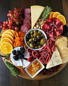 a wooden platter filled with different types of cheeses and fruit on top of it