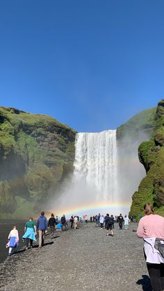 people standing in front of a waterfall with a rainbow