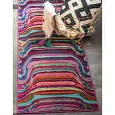 a multicolored rug is laying on the floor next to a pillow and bag