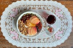 a white plate topped with fruit and granola next to a glass of red wine