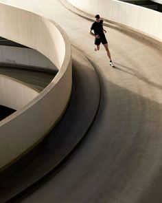 a man is running down the road in front of some curved concrete walls and stairs