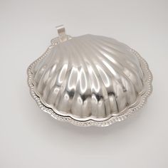 a silver shell shaped dish on a white surface