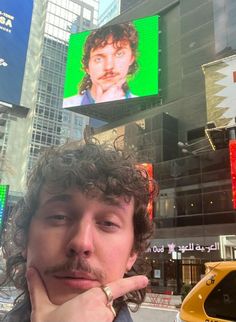 a man is standing in front of a building with billboards on the side of it