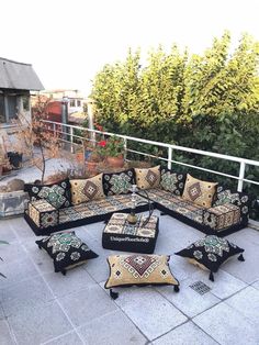 a couch and ottoman on a patio with trees in the background