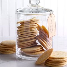 a glass jar filled with cookies on top of a white marble counter next to a pile of crackers