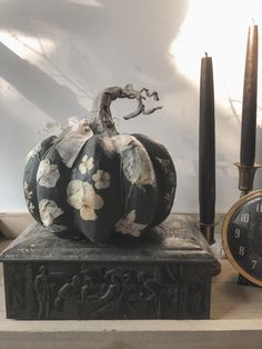 a black and white pumpkin sitting on top of a table next to an alarm clock