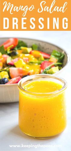 mango salad dressing in a glass jar next to a bowl of fresh fruit and vegetables