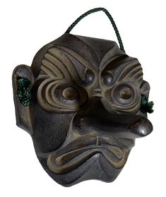 a mask hanging from the side of a wall with green beads on it's face