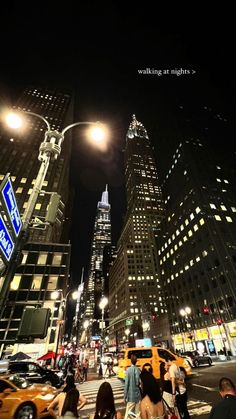 people crossing the street at night in front of tall buildings and skyscrapers on a busy city street