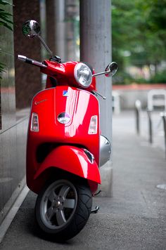 a red scooter parked next to a building