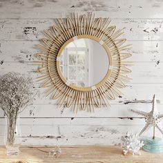 a mirror on the wall next to a vase with flowers and starfish in it