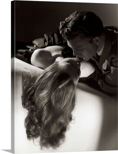 black and white photograph of a man kissing a woman's head with long hair