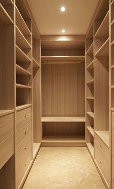 an empty walk - in closet with wooden shelves and drawers on both sides, lighting from the ceiling